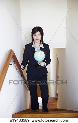 Portrait of a businesswoman holding a globe and walking on the staircase View Large Photo Image Stock Photo - Portrait of a businesswoman holding a globe and walking on the staircase. Fotosearch