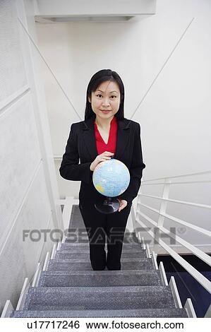Stock Photograph - Portrait of a businesswoman holding a globe and smiling. Fotosearch