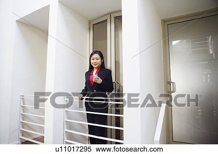 Stock Photography - Portrait of a businesswoman holding a mobile phone and smiling. Fotosearch