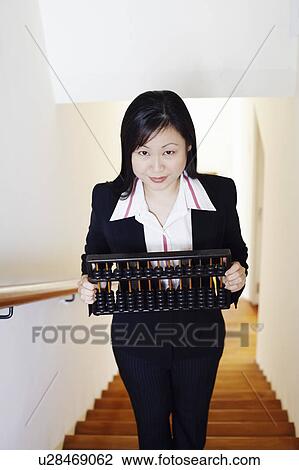 Portrait of a businesswoman holding an abacus and standing on the staircase View Large Photo Image Stock Image - Portrait of a businesswoman holding an abacus and standing on the staircase. Fotosearch