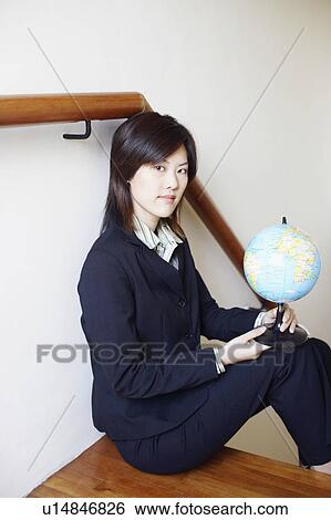 Portrait of a businesswoman sitting on a staircase and holding a globe View Large Photo Image Stock Photograph - Portrait of a businesswoman sitting on a staircase and holding a globe. Fotosearch