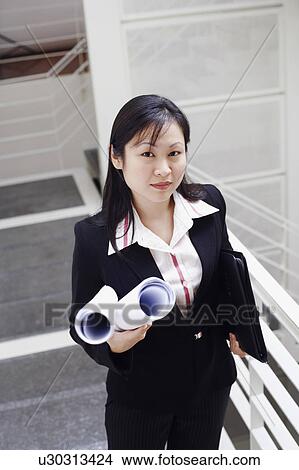 Picture - Portrait of a female architect holding rolled up blueprints. Fotosearch