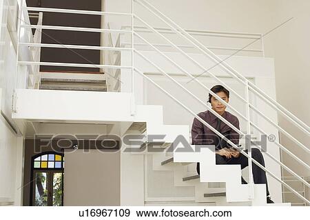 Stock Photo - Portrait of a male customer service representative sitting on the staircase. Fotosearch