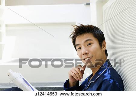 Stock Photo - Portrait of a mid adult man holding a newspaper. Fotosearch