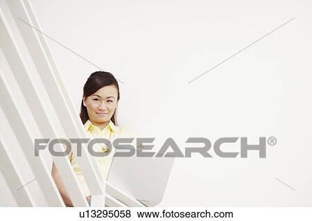 Portrait of a young woman using a laptop and smiling View Large Photo Image Stock Photo - Portrait of a young woman using a laptop and smiling. Fotosearch