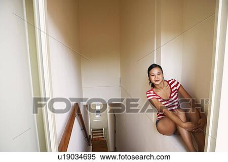 Stock Photography - Young woman sitting on a ledge and smiling. Fotosearch