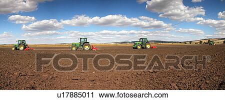 Stock Image - Tractors working the field. Fotosearch