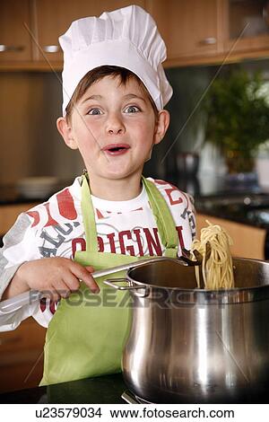 Picture - Boy cooking spaghetti. Fotosearch