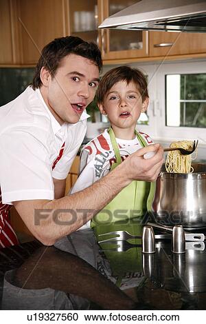 Stock Image - Father and son cooking spaghetti. Fotosearch