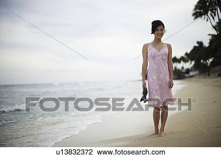 A woman walking on beach with sandal in hand View Large Photo Image Stock Image - A woman walking on beach with sandal in hand. Fotosearch