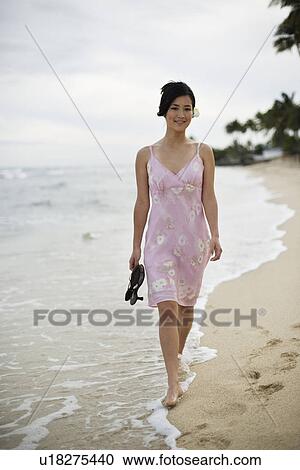 A woman walking on beach with sandal in hand View Large Photo Image Stock Image - A woman walking on beach with sandal in hand. Fotosearch