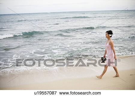 A woman walking on beach with sandal in hand View Large Photo Image Stock Photo - A woman walking on beach with sandal in hand. Fotosearch