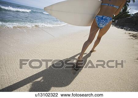 A woman walking on beach with surfboard View Large Photo Image Stock Image - A woman walking on beach with surfboard. Fotosearch