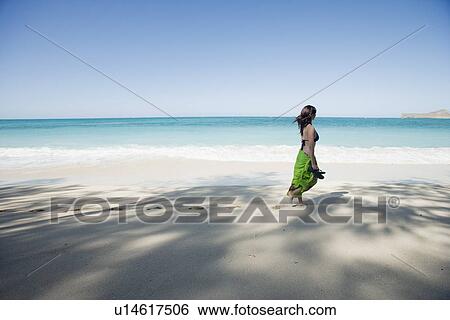 Stock Photograph - A young woman walking on beach. Fotosearch