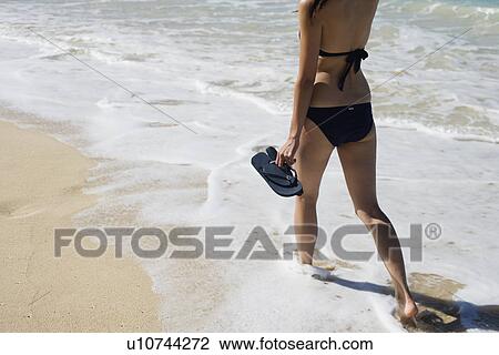 Stock Image - Low section of a woman walking on beach. Fotosearch