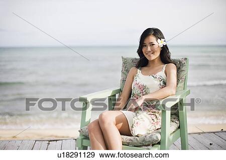 Portrait of a woman sitting on chair at beach View Large Photo Image Stock Photo - Portrait of a woman sitting on chair at beach. Fotosearch