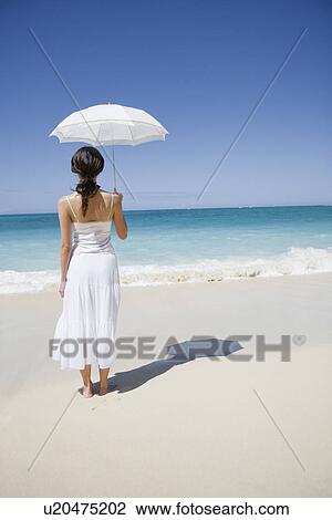 Rear view of a woman standing on beach View Large Photo Image Stock Image - Rear view of a woman standing on beach. Fotosearch