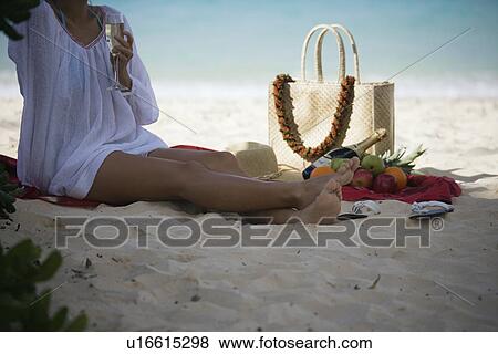 A woman holding wineglass sitting on beach View Large Photo Image Stock Photo - A woman holding wineglass sitting on beach. Fotosearch