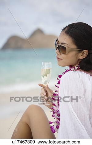 A young woman holding wineglass sitting at beach View Large Photo Image Stock Photo - A young woman holding wineglass sitting at beach. Fotosearch