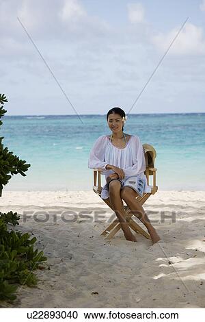 A young woman sitting on chair at beach View Large Photo Image Stock Image - A young woman sitting on chair at beach. Fotosearch