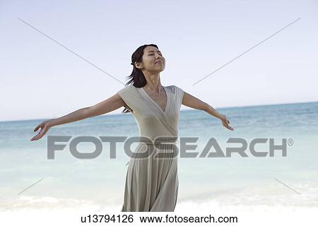 A young woman with arms outstretching at beach View Large Photo Image Stock Photograph - A young woman with arms outstretching at beach. Fotosearch