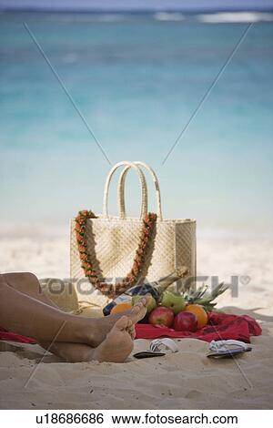 Stock Photograph - Low section of a woman sitting on beach. Fotosearch