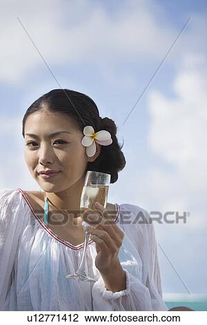 Stock Image - Portrait of young woman holding wineglass. Fotosearch