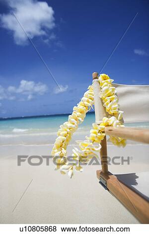 View of a flower garland hanging on wooden chair at beach View Large Photo Image Stock Photo - View of a flower garland hanging on wooden chair at beach. Fotosearch