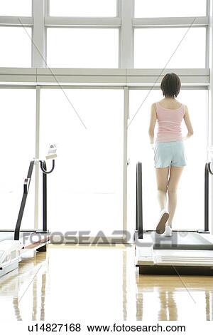 A young woman jogs on a walker as she exercises in a well equipped gym View Large Photo Image Stock Photo - A young woman jogs on a walker as she exercises in a well equipped gym. Fotosearch
