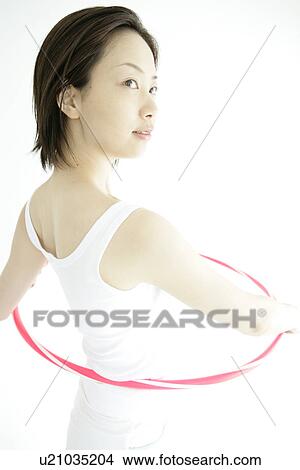 A young woman stands inside hula hoop as she gets ready for a hip exercise View Large Photo Image Picture - A young woman stands inside hula hoop as she gets ready for a hip exercise. Fotosearch