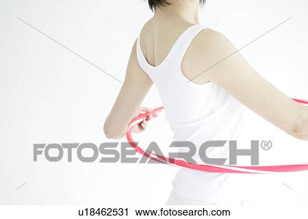 Stock Image - A young woman stands inside hula hoop as she gets ready for a hip exercise. Fotosearch