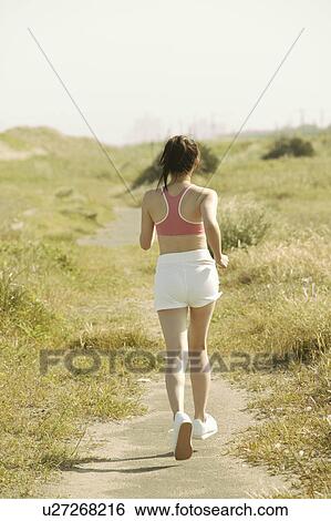 Rear view of a woman jogging in a remote area View Large Photo Image Stock Photograph - Rear view of a woman jogging in a remote area. Fotosearch