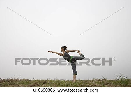 Stock Photography - View of a young woman balancing on one leg. Fotosearch