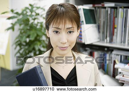 A woman holding a diary stands beside the library View Large Photo Image Stock Image - A woman holding a diary stands beside the library. Fotosearch