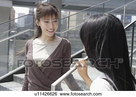 Stock Photograph - A woman sharing a joke with her friend. Fotosearch