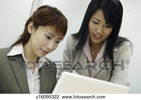 Stock Image - Two women pleased as they look over the laptop. Fotosearch