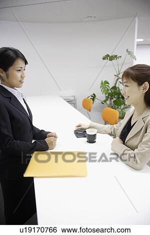 Two women smiling at each other at the reception View Large Photo Image Stock Photograph - Two women smiling at each other at the reception. Fotosearch