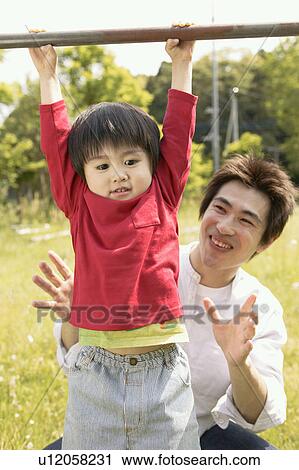 A small boy lifts himself on to a rod as his father looks on View Large Photo Image Stock Image - A small boy lifts himself on to a rod as his father looks on. Fotosearch