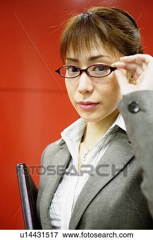A businesswoman holding her glasses faces the camera View Large Photo Image Stock Photo - A businesswoman holding her glasses faces the camera. Fotosearch