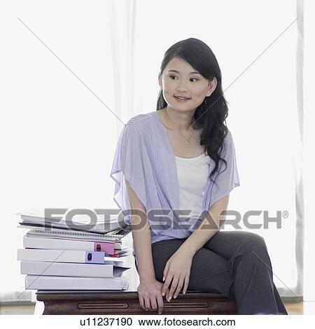 Stock Image - Businesswoman sitting on a table with her legs crossed. Fotosearch