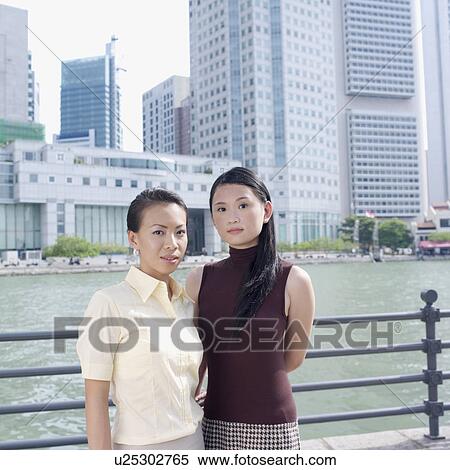 Portrait of two businesswomen standing in front of a railing View Large Photo Image Stock Photography - Portrait of two businesswomen standing in front of a railing. Fotosearch