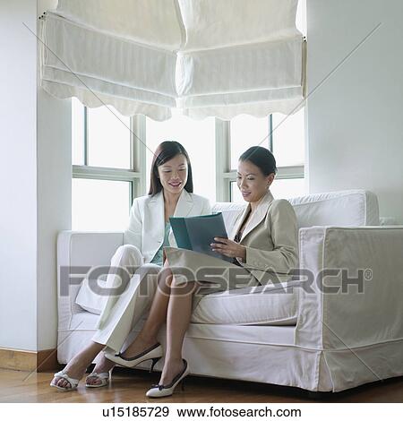 Two businesswomen reading a file View Large Photo Image Stock Photo - Two businesswomen reading a file. Fotosearch