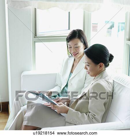 Two businesswomen sitting on a couch View Large Photo Image Picture - Two businesswomen sitting on a couch. Fotosearch
