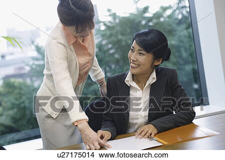 Two women exchange happiness as they look over the file View Large Photo Image Picture - Two women exchange happiness as they look over the file. Fotosearch