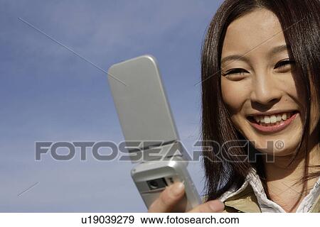 Close-up of a young woman looking at a cellphone View Large Photo Image Stock Photo - Close-up of a young woman looking at a cellphone. Fotosearch