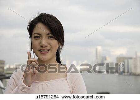 Portrait of a smiling young woman using mobile phone View Large Photo Image Picture - Portrait of a smiling young woman using mobile phone. Fotosearch