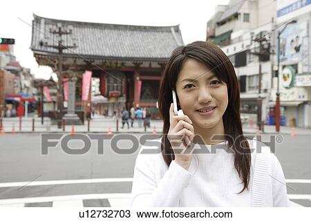 Portrait of a smiling young woman using mobile phone View Large Photo Image Stock Image - Portrait of a smiling young woman using mobile phone. Fotosearch
