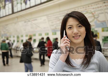 Portrait of a smiling young woman using mobile phone at the station View Large Photo Image Stock Image - Portrait of a smiling young woman using mobile phone at the station. Fotosearch