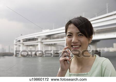 Portrait of a smiling young woman using mobile phone View Large Photo Image Stock Image - Portrait of a smiling young woman using mobile phone. Fotosearch