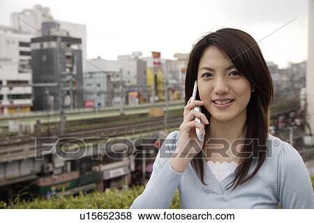 Portrait of a smiling young woman using mobile phone View Large Photo Image Stock Photo - Portrait of a smiling young woman using mobile phone. Fotosearch